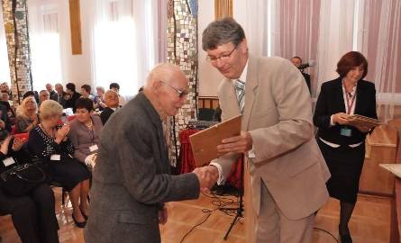 Dyrektor Dariusz Łuczak wręcza dyplom najstarszemu absolwentowi Jerzemu Wiśniewskiemu.