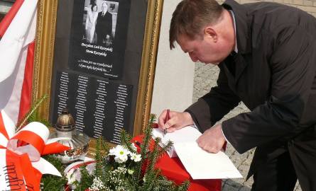 Wójt Radomyśla nad Sanem Jan Pyrkosz wpisuje się do księgo kondolencyjnej przy krzyżu przy bazylice w Stalowej Woli.