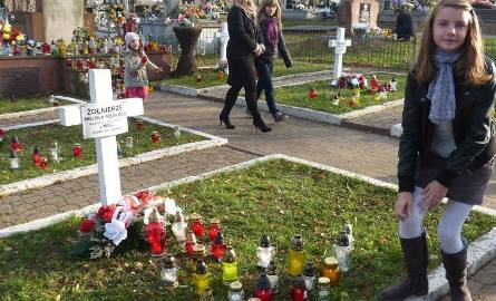 Zuzia Ocetek zapala znicz na cmentarzu poległych w 1939 roku żołnierzy w Łącznej.