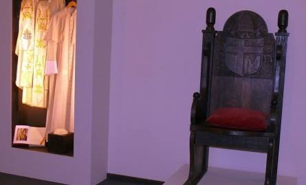 Replika tronu z czarnego dębu, na którym siedział papież oraz biała sutanna z pelerynką i piuska.
