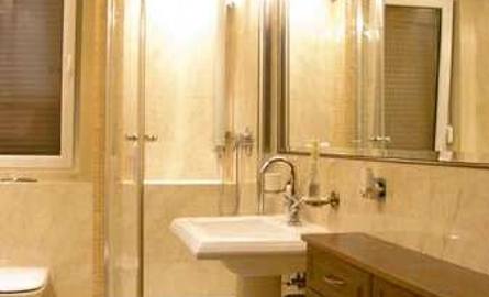 Wąską łazienkę optycznie powiększa duże lustro zamontowane na jednej ze ścian