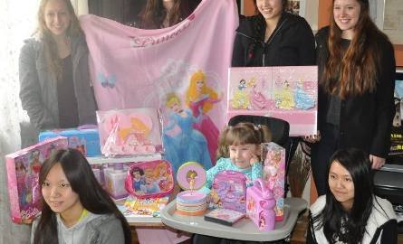 Wszystkie prezenty są w różowym kolorze. Ula jest bardzo szczęśliwa. Na zdjęciu z wolontariuszkami z Fundacji Dziecięca Fantazja
