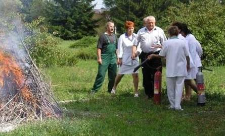 Personel medyczny testuje gaśnice szpitalne na stercie zapalonego drzewa.