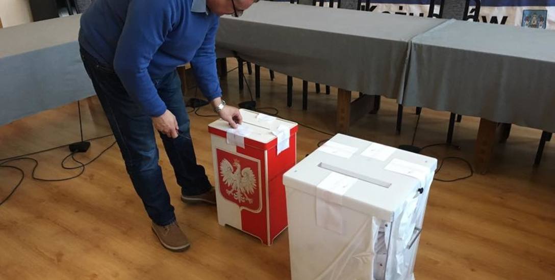 Przewodniczący komisji Grzegorz Wajman zrywa zabezpieczenia z urn zawierających głosy