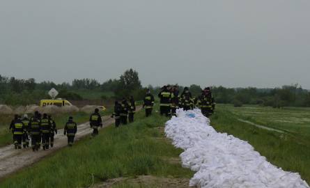 Strażacy podwyższają workami z piaskiem wał w sandomierskim Koćmierzowie.