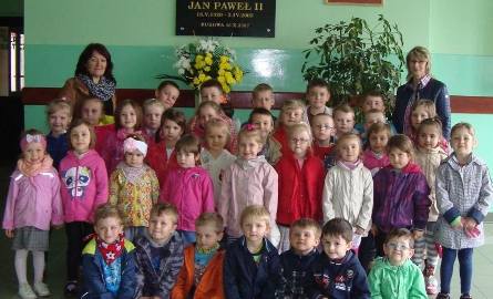 Przedszkolaki z Bukowy przed tablicą pamiątkową świętego patrona szkoły.