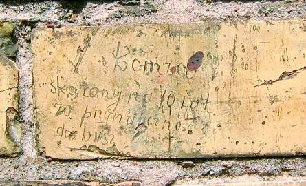Napis na murze wydrapany przez więźnia: Łomża, skazany na 10 lat za przynależność do (W)NSZ