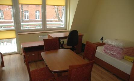 Centralne miejsce w dużym pokoju zajmuje stół, pod oknem są biurka.