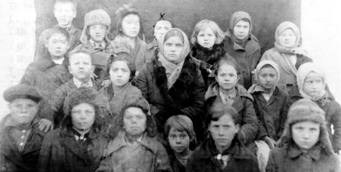 Dzieci w szkole na Syberii. Krzyżykiem nad głową zaznaczony Stanisław Szwajkowski
