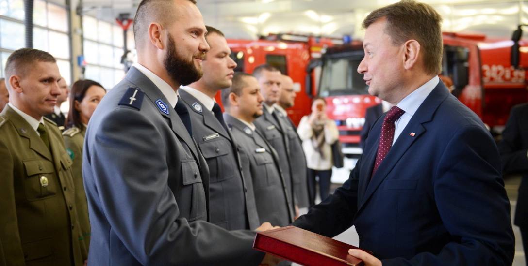 Minister administracji Mariusz Błaszczak wręecza pamiątkową plakietkę Pawłowi  Lorentowiczowi  ze straży granicznej