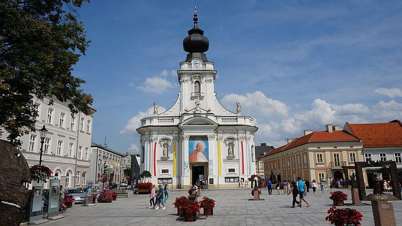 Karol Wojtyła urodził się w Wadowicach 18 maja 1920 roku. W czasie porodu przez otwarte okno jego mama słyszała dochodzący z kościoła śpiew litanii do Matki Bożej. Na ścianie kościoła był zegar słoneczny z napisem. Jakim?